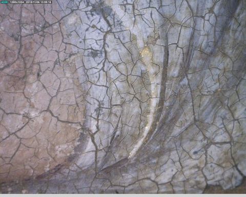 Painting. Detail view of a cracked painted surface with a few shimmering specks of gold lining an edge of powder-blue clothing.