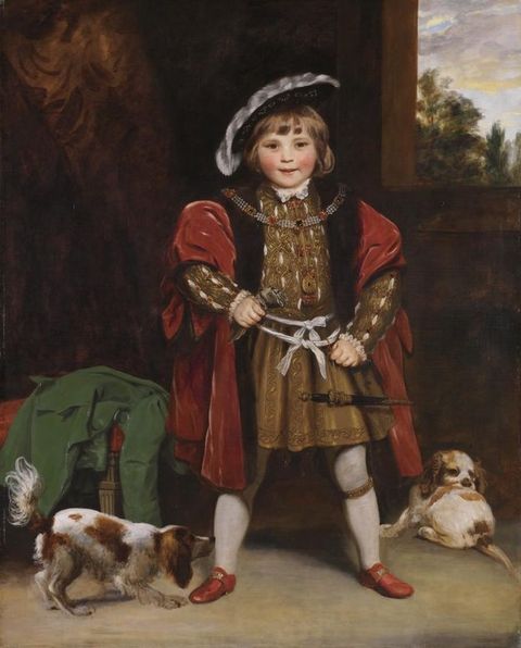Painting. A young boy with pale skin and rosy, round cheeks stands with feet widely planted, grinning at us. He wears a gold tunic slitted so the white linen underneath can be seen. A ruby-red, velvet robe drapes over his shoulders, and one hand rests on the hilt of a sword hanging by his side.